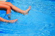 Young girls legs splashing water in swimming pool. Summer holiday. Copy space.