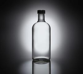 Glass bottle on black background with spotlight