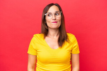Wall Mural - Middle-aged caucasian woman isolated on red background having doubts while looking up