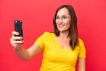 Wall Mural - Middle-aged caucasian woman isolated on red background making a selfie