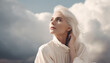 A beautiful middle age woman with white hair sitting in front of clouds looking to sky, copy space, template, generative ai