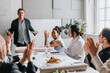 © Maskot - Male and female business people applauding for manager during meeting at work place