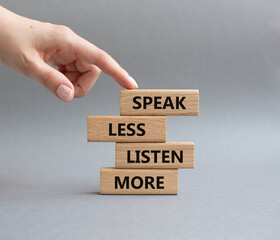 Speak less Listen more symbol. Wooden blocks with words Speak less Listen more. Beautiful grey background. Businessman hand. Business and Speak less Listen more concept. Copy space.