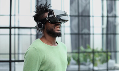 Cool handsome african american man put on virtual reality goggles for the first time in the office.