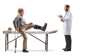 Wall Mural - Doctor writing a prescription and an elderly male patient sitting on a physical therapy bed with a brace on his leg