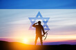 © hamara - Silhouette of soldier saluting against the sunrise in the desert and Israel flag.