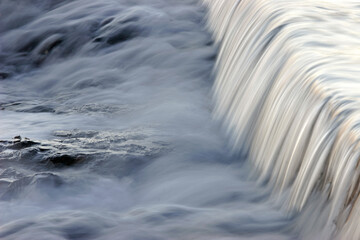 Poster - Flowing water taken with a slow shutter speed on a rocky beach