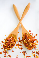 Wall Mural - red pepper flakes on a wooden spoon over following