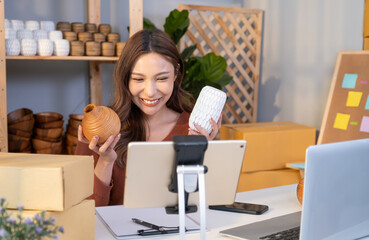 Young Asian female entrepreneur smile while talking on the phone and check customer order from online shopping inside of home office. New small business start up trend with online marketing