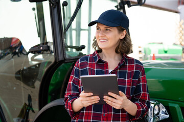 Aufkleber - Woman farmer with a digital tablet on the background of an agricultural tractor	
