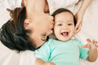 © Clement C/peopleimages.com - Top view, bed and mother kiss baby for bonding, quality time or loving support together at home. Newborn face, portrait or above of mom and happy infant for care, relationship or affection in bedroom