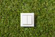 electricity, energy and power consumption concept - close up of light switch on green grass background