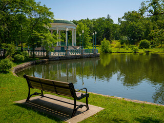 Wall Mural - Tranquil lake landscape with a bench,  water reflections, and Bandstand Pavillion on Roosevelt Lake at Roger Williams Park in Providence, Rhode Island