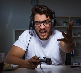 Wall Mural - Young man playing games long hours late in the office