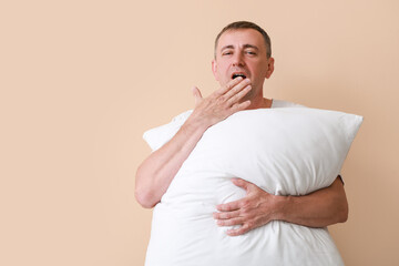 Canvas Print - mature man with soft pillow yawning on beige background