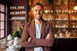 © Hanne Bauer - Portrait of a smiling man standing with arms crossed in a coffee shop