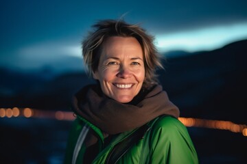 Wall Mural - Portrait of a smiling woman in a green jacket and scarf on the background of the evening city