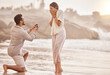 © Azeemud-Deen Jacobs/peopleimages.com - Couple at beach, wow for proposal and engagement with love and commitment with ocean and people outdoor. Travel, mockup space and man propose marriage to woman, surprise and happiness with care