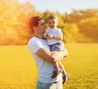 © guas - Summer sunny portrait of happy smiling young father holding little child son walking in the park together