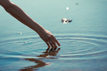 hand touching water surface making ripples	