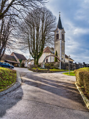 Poster - St Joseph church on the street during beautiful sunshine through the trees, Kamnik, Slovenia