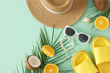 Idea Of A Coastal Summer Getaway. Top View Flat Lay Of Yellow Flip Flops, Sun Hat, Sunglasses, Shell Bracelet, Orange Fruit, Palm Leaves And Coconuts On Teal Background With Space For Promo Or Text