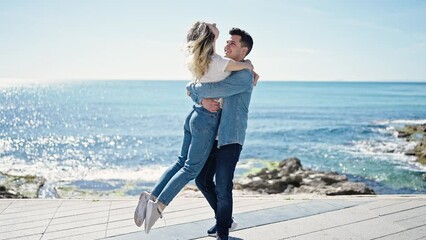 Poster - Man and woman couple smiling confident hugging each other turning at seaside