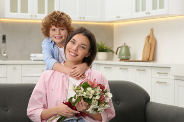 Poster - Little son congratulating his mom with Mother`s day at home, space for text. Woman holding bouquet of beautiful flowers