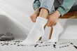© New Africa - Woman putting on white socks at home, closeup
