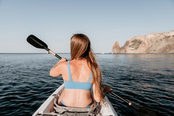 Woman in kayak back view. Happy young woman with long hair floating in kayak on calm sea. Summer holiday vacation and cheerful female people relaxing having fun on the boat.