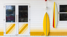Colorful Facade Wall With Surfboards Hanging On It With Door And Window Background.
