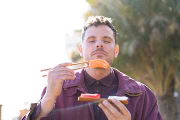 Wall Mural - Young caucasian man eating sashimi at outdoors