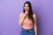 © luismolinero - Young caucasian woman isolated on purple background showing a sign of silence gesture putting finger in mouth