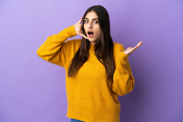 Wall Mural - Young caucasian woman isolated on purple background making phone gesture and doubting