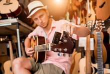 Young Musician Tuning A Classical Guitar In A Guitar Shop
