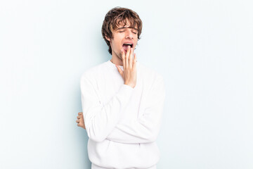 Wall Mural - Young caucasian man isolated on blue background yawning showing a tired gesture covering mouth with hand.