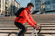 © muse studio - A cyclist is smiling happily, a man is riding around the city in a helmet to the office with a bag. Urban transport for people.