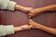 Support, empathy and people holding hands at school for trust, love and respect. Together, sorry and above of friends or students with a helping hand, forgiveness or compassion at a desk in college