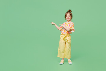 Wall Mural - Full body little child kid girl 6-7 years old wear casual clothes point index finger aside on area isolated on plain pastel green background studio portrait Mother's Day love family lifestyle concept