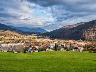 Poster - Kamnik village valley, lush green grass field and mountain in the background with dramatic clou, Kamnik, Slovenia