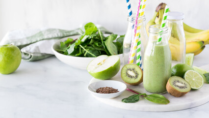 Wall Mural - A green smoothie in a bottle surrounded by fresh ingredients to make it.