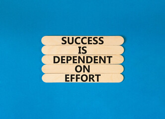 Wall Mural - Success and effort symbol. Concept words Success is dependent on effort on wooden stick. Beautiful blue table blue background. Business success and effort concept. Copy space.