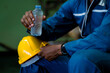 © KANGWANS - Worker drinking water from bottle during work break. Stay hydrated at work.