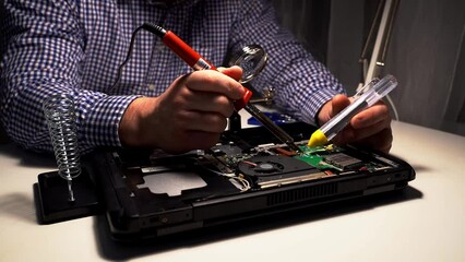 Wall Mural - a man is soldering in a repair shop. repair of the board with a soldering iron