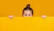 kid hiding behind blank yellow paper with copy space for advertisement