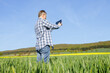 © Elena Medoks - A man with a digital tablet in his hands in a rye field. The farmer inspects the crop and writes down the readings on the tablet. Technologies in agriculture.