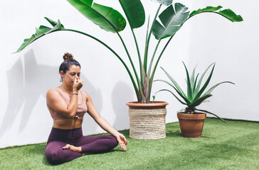 Caucasian fitness girl sitting in asana for training vitality wellness and tranquility, slim woman in casual sportive wear recreating on meditation in lotus pose practice yoga for health at terrace