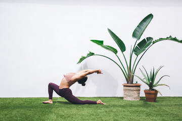 Wall Mural - Strong Caucasian female in active wear standing in asana with raised hands concentrated on keeping body shape, woman 20s enjoying yoga training at terrace feeling vitality inspiration and balance