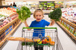 © Volodymyr - Kid with shopping cart and vegetables at grocery store. Kid is choosing fresh vegetables and fruits in the store. Child buying food in grocery supermarket.