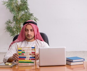Wall Mural - Young male arab employee working in the office